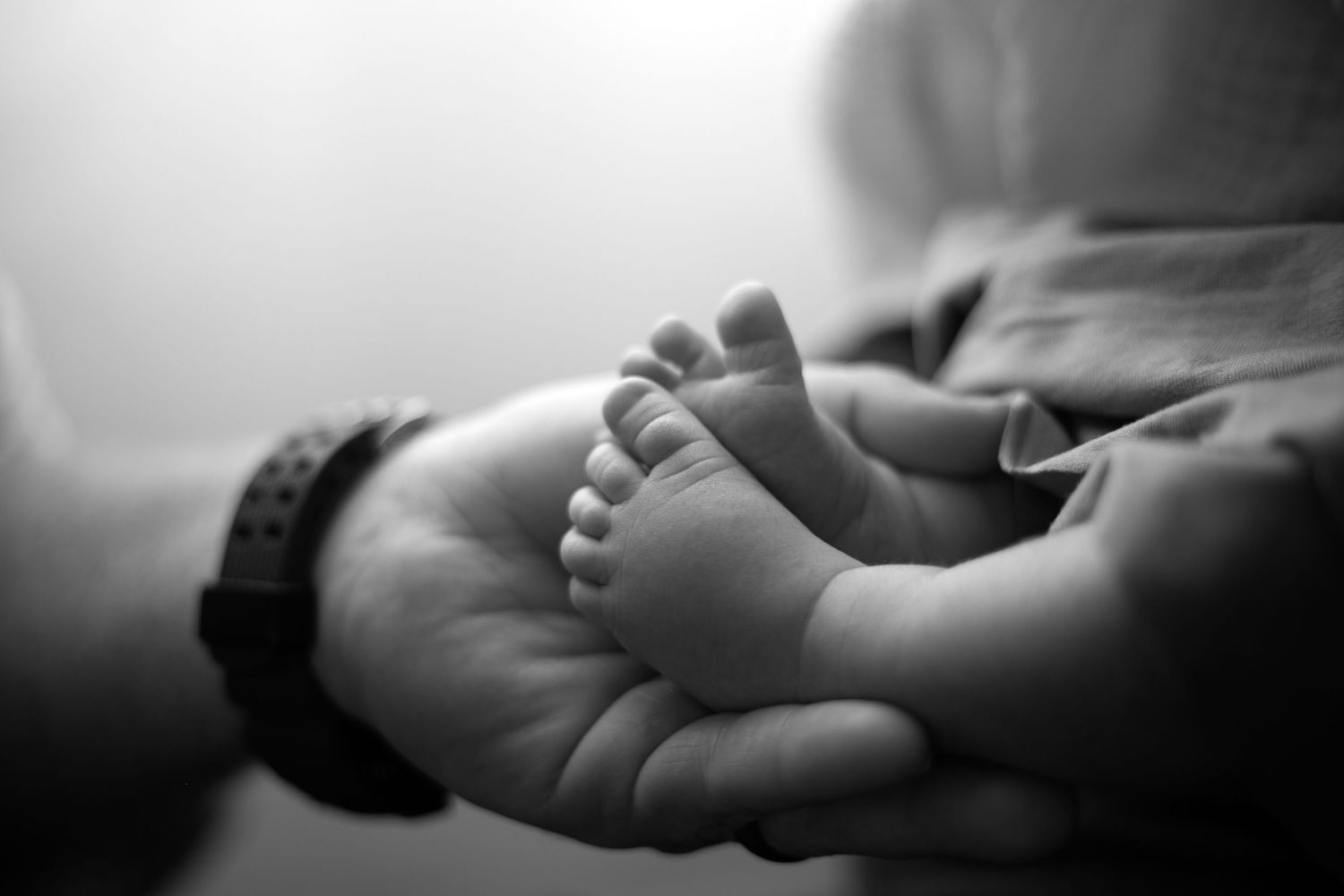 Seven black and white photos showing tiny baby feet in a row, creating a tender newborn photography composition.