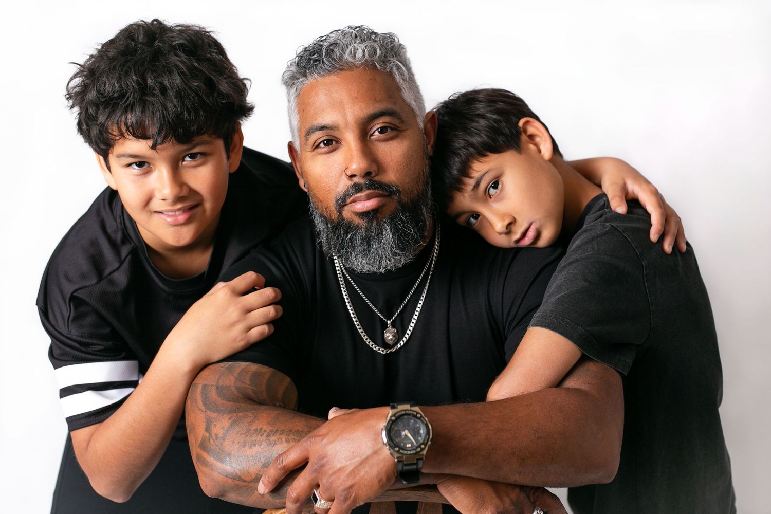 Family portrait with three people wearing black shirts against white background.
