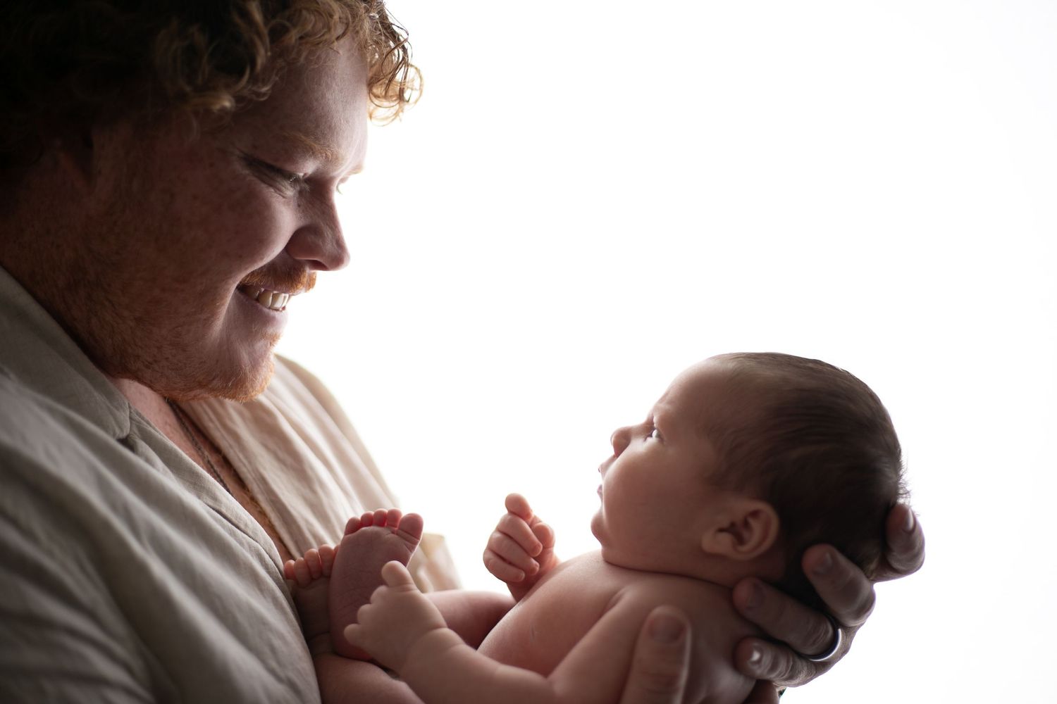 A tender moment between parent and baby in silhouette against soft window light.