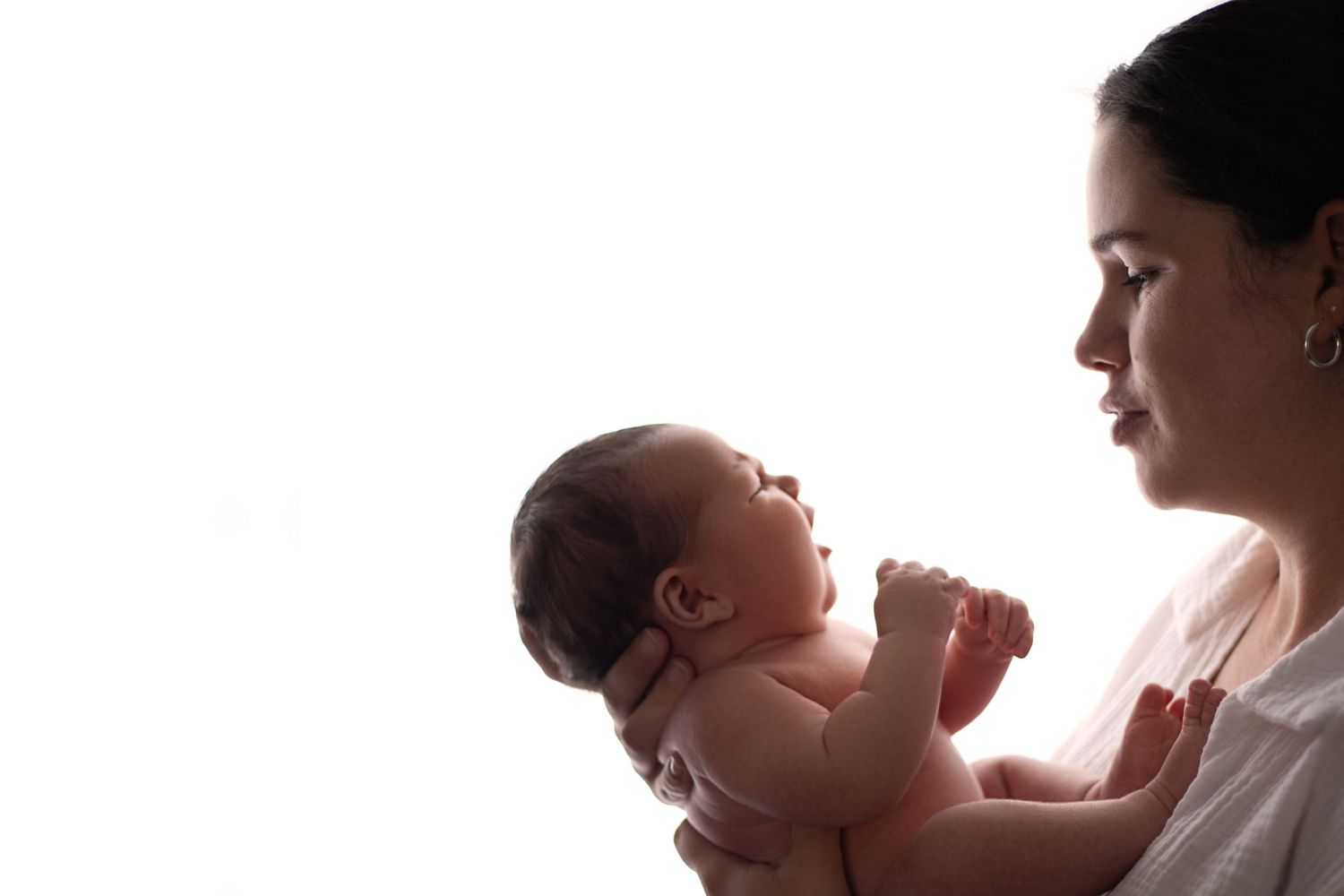 A silhouetted profile view of a parent and baby against a bright window background.