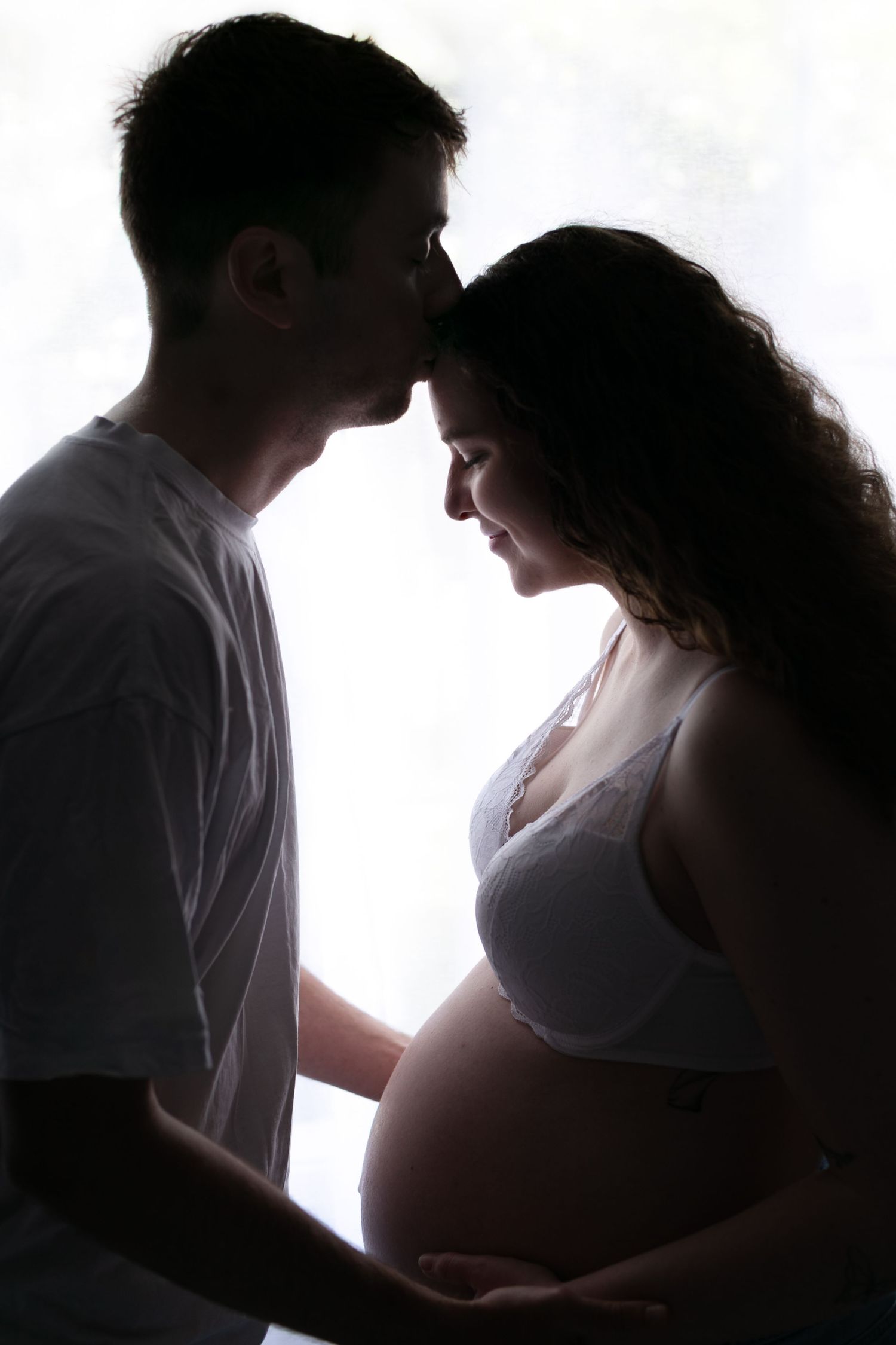 A series of silhouetted figures in an intimate moment against bright backlighting creates a romantic sequence.