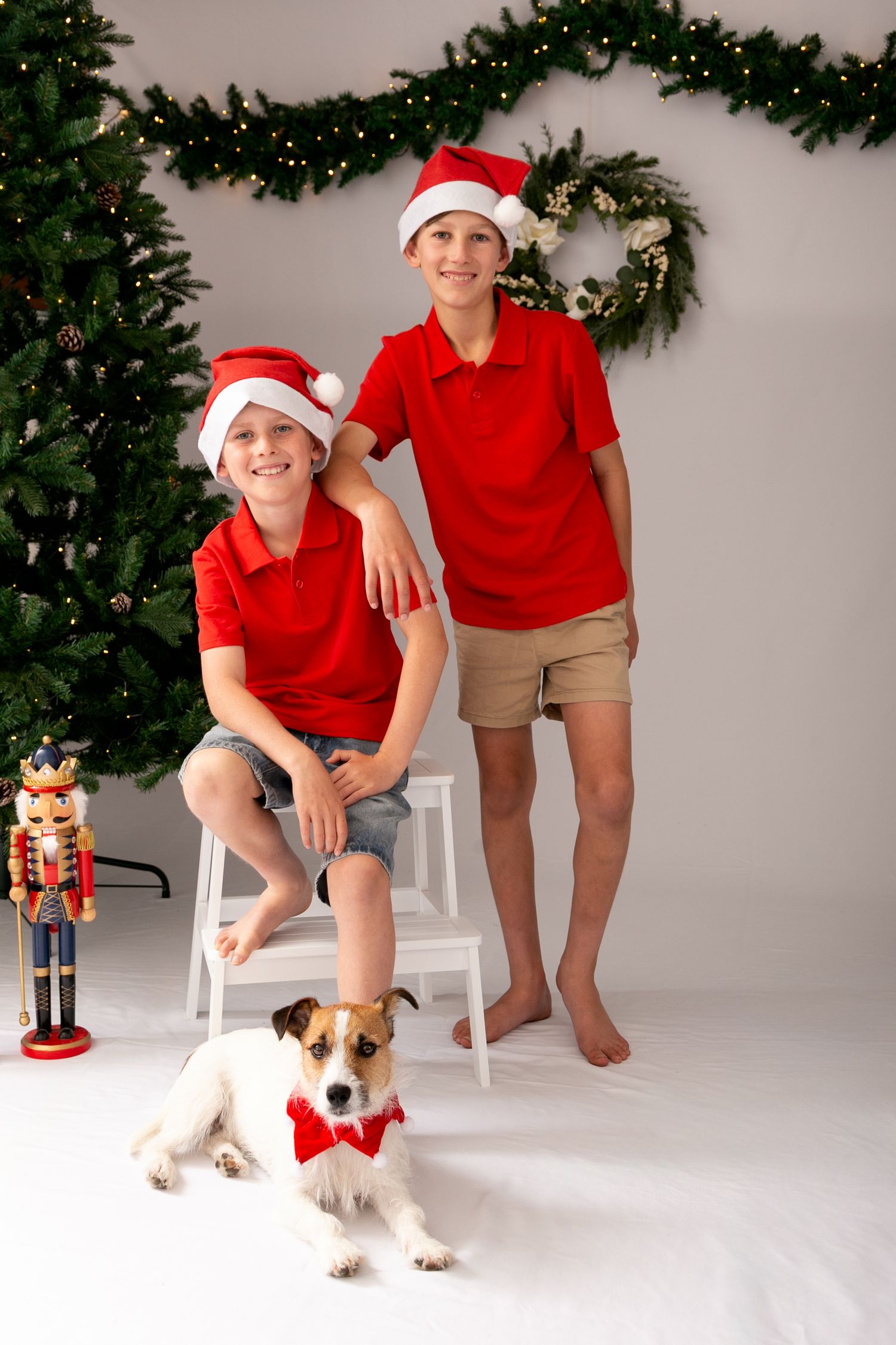 A festive holiday photo series with a small dog in a Santa outfit next to a decorated Christmas tree and nutcracker decor.