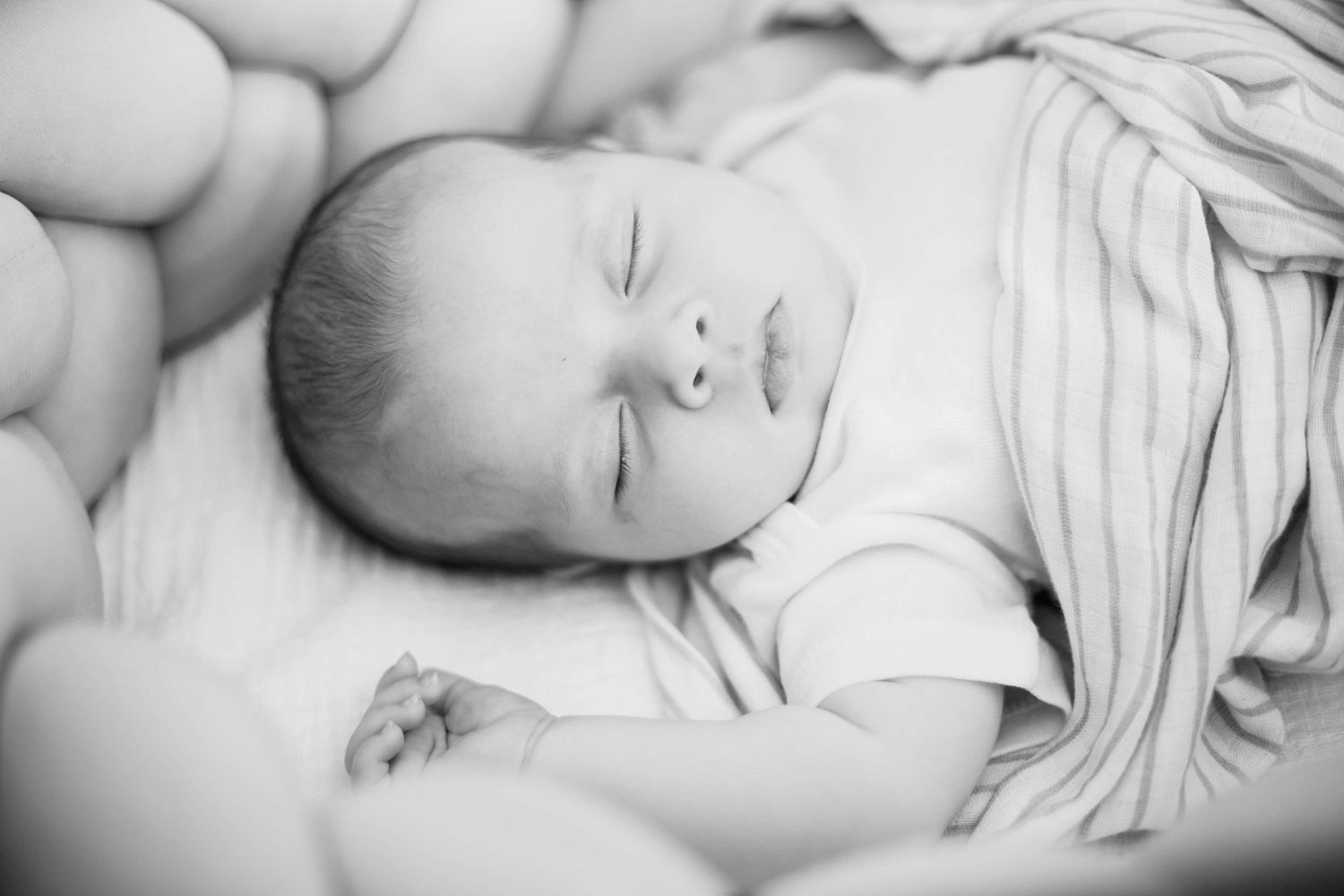 Black and white photos of a sleeping newborn baby wrapped in soft white fabric.