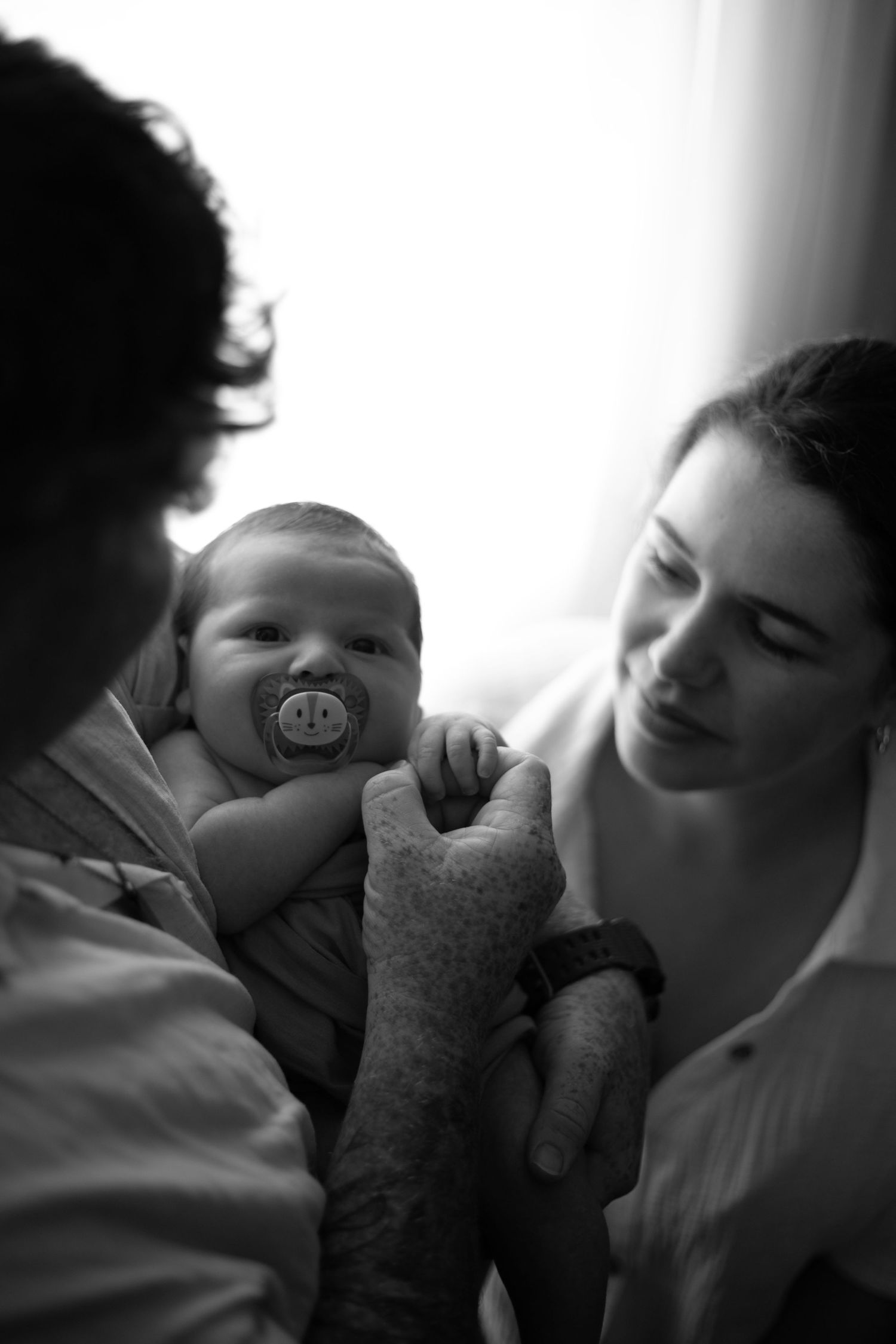 A series of intimate black and white photos showing tender moments between a parent and baby.