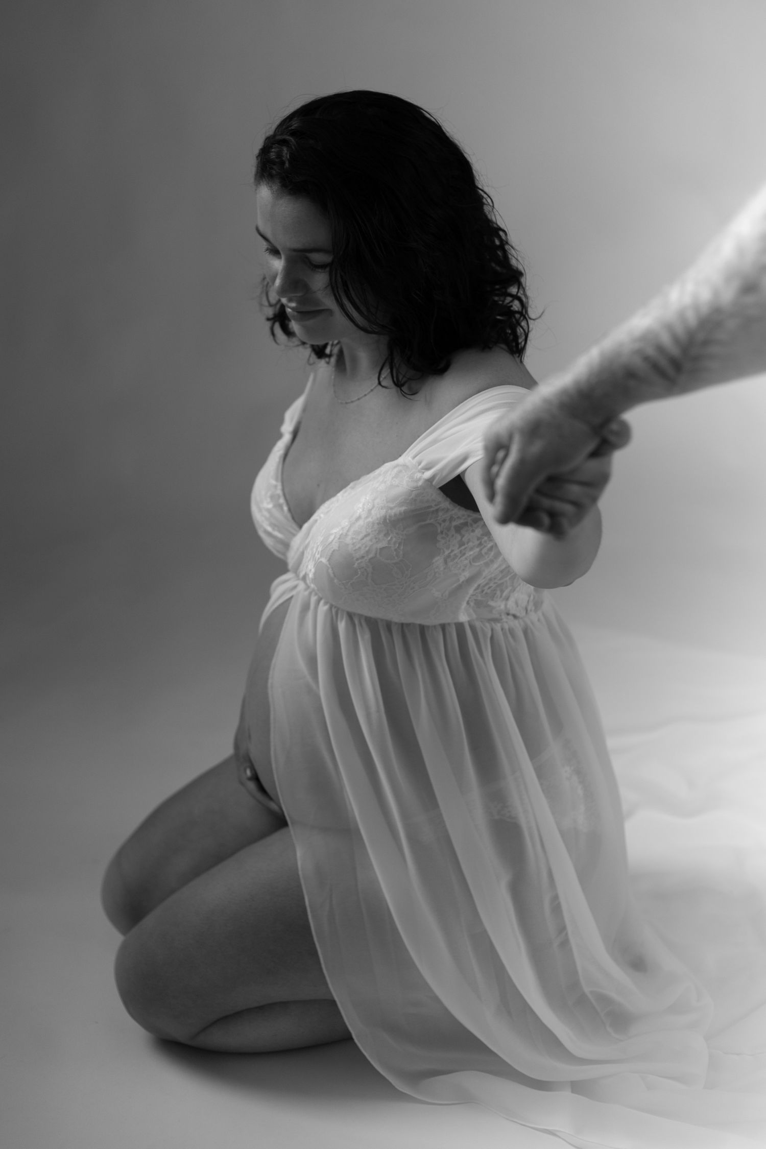 Artistic black and white photo series showing a figure in flowing white fabric reclining in minimalist poses.