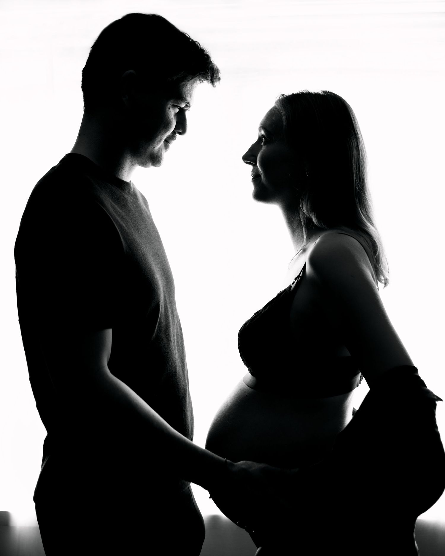 A series of black and white silhouettes showing the progression of pregnancy stages from conception to full term.