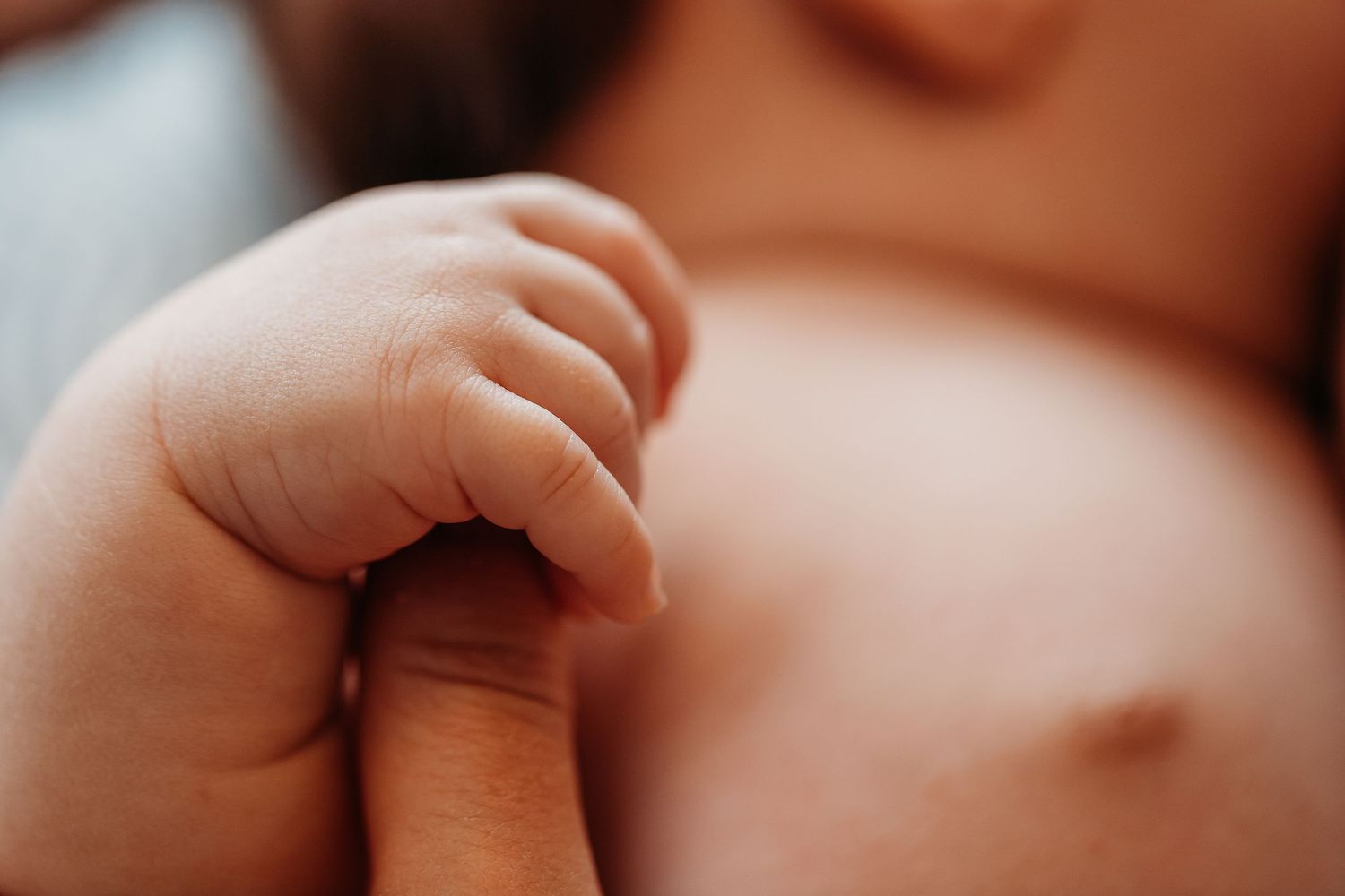 Gros plans détaillés de minuscules doigts de bébé sous une douce lumière naturelle.