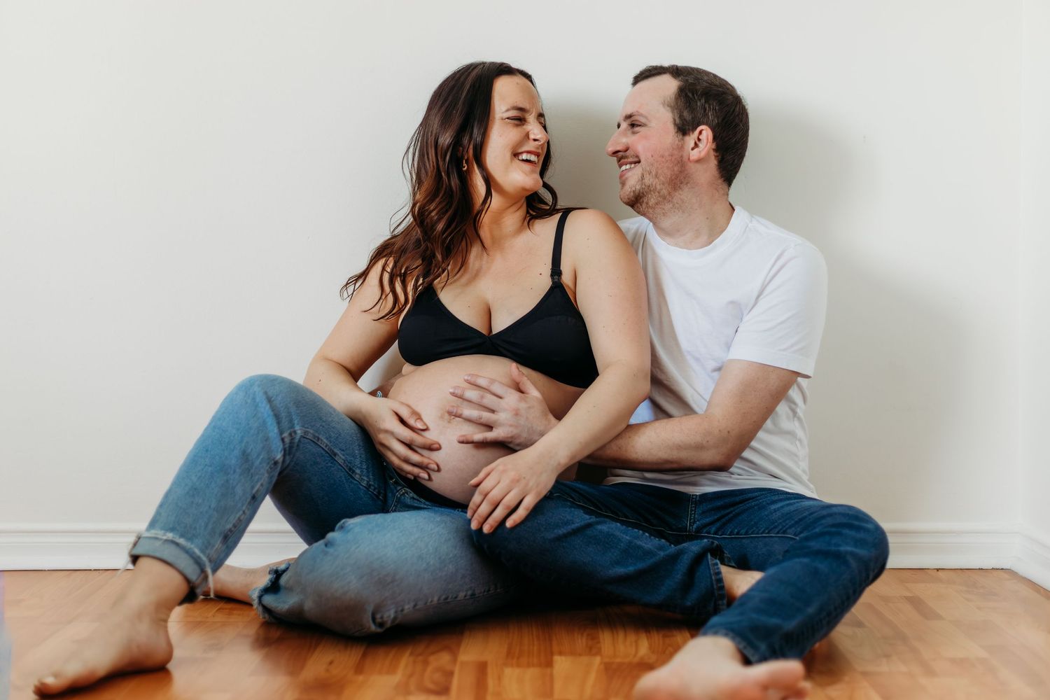 Casual indoor couple photography session with minimalist white background.