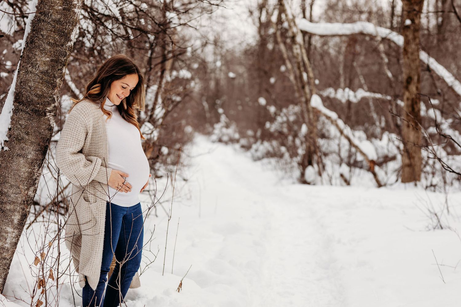 A romantic winter engagement photo session with a couple embracing in a snowy forest landscape.