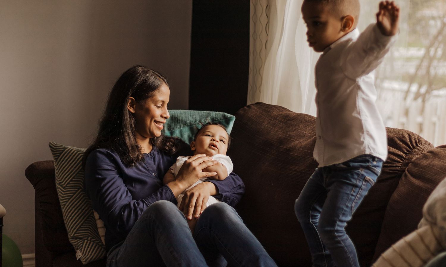 Une famille partageant des moments intimes dans un cadre intérieur chaleureux baigné de lumière naturelle.