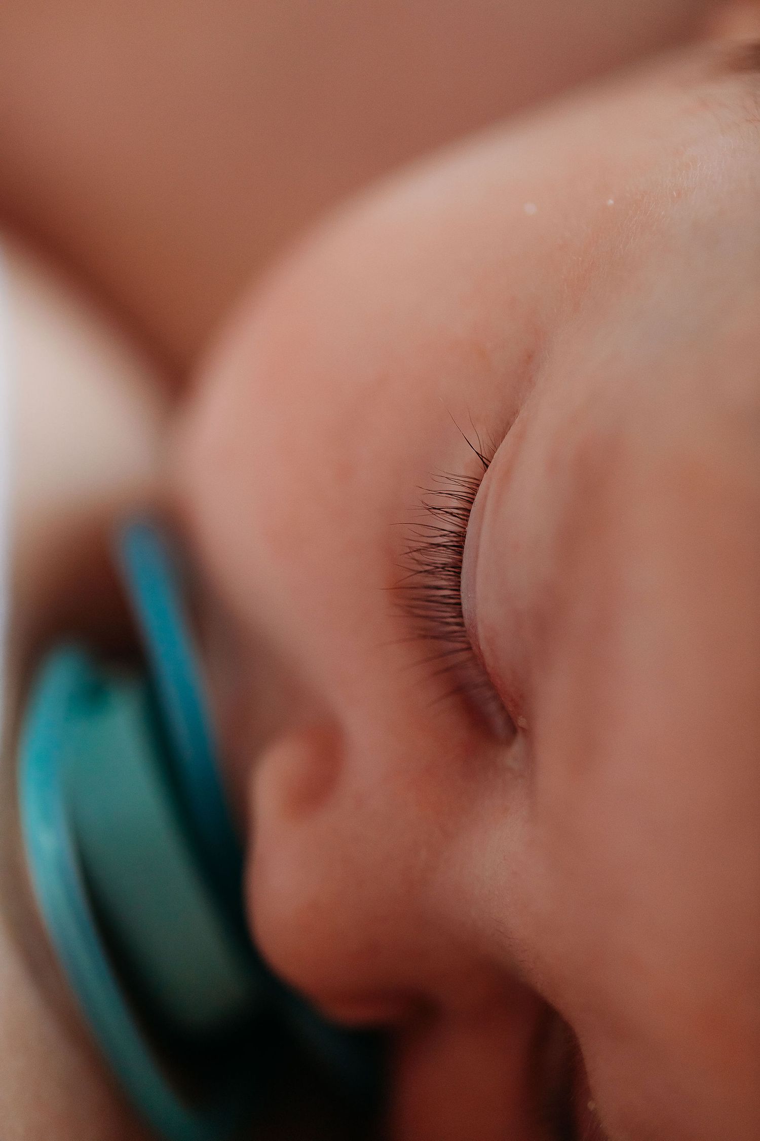 Close-up macro shot of long eyelashes and eye makeup in a soft, warm-toned setting.