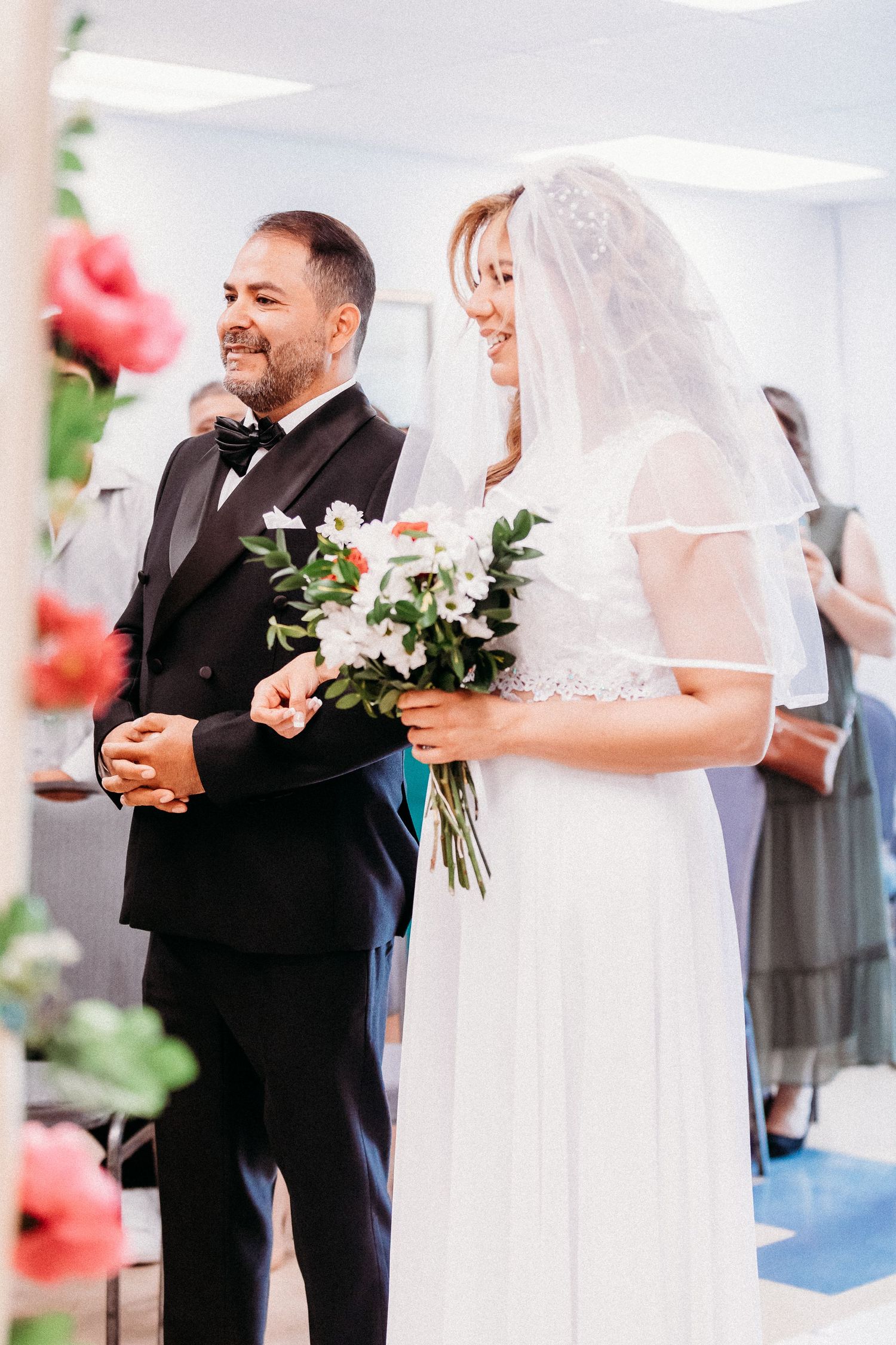 Un moment de joie lors d'une cérémonie de mariage où un couple échange ses vœux devant des colonnes blanches.