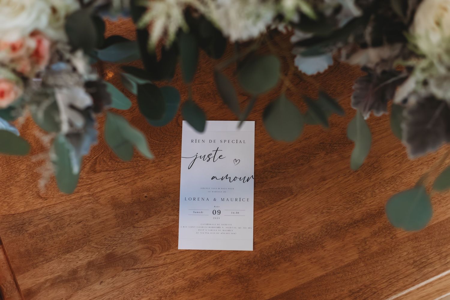 Gros plan sur une élégante papeterie de mariage ornée de fleurs blanches et de verdure sur une table en bois.