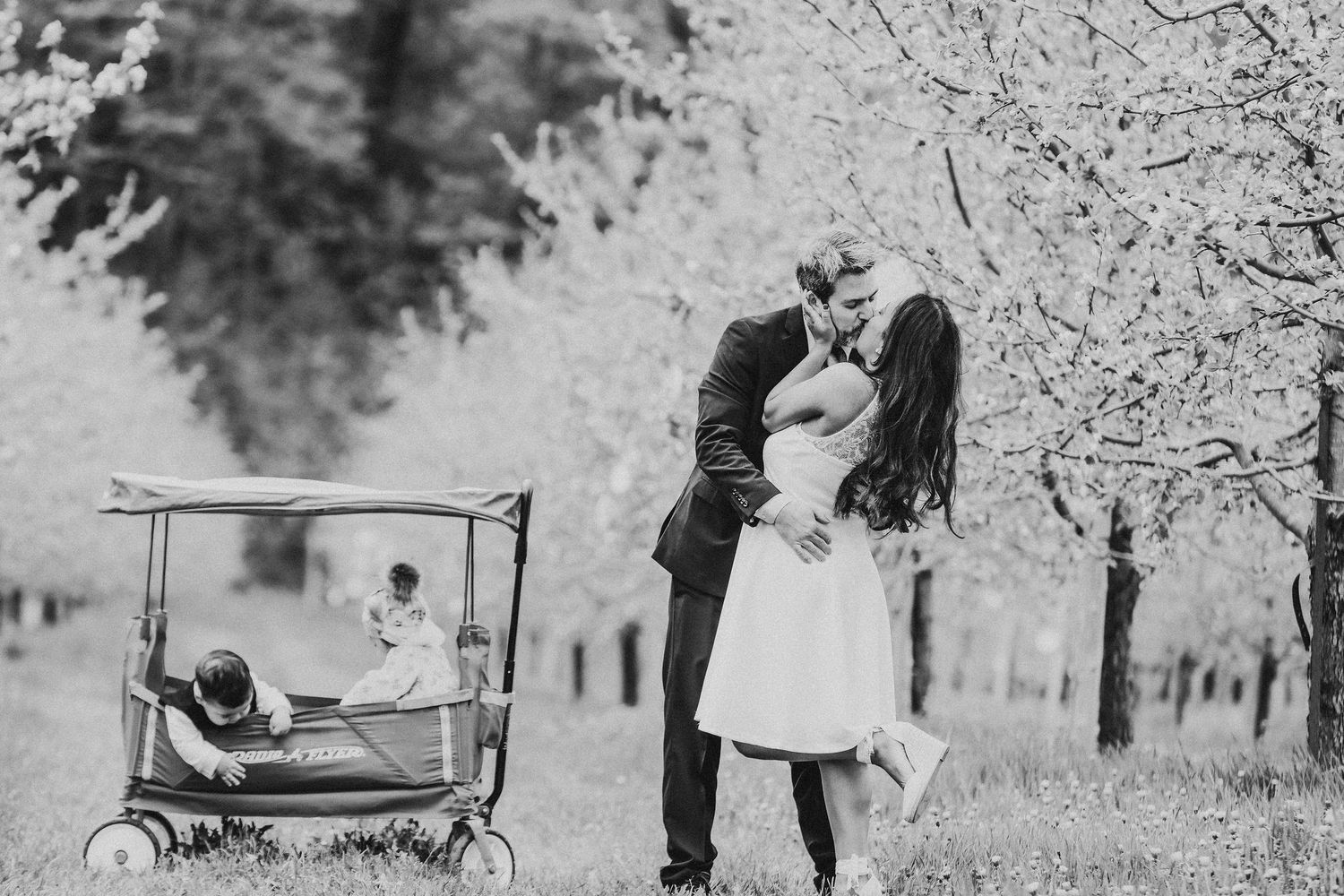 Vintage black and white photograph showing a couple in formal attire walking together in a garden setting.