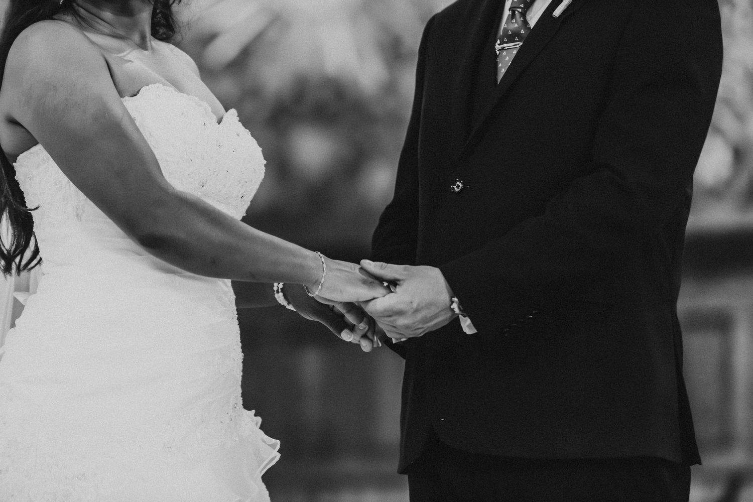 Photo en noir et blanc de l'échange des vœux lors d'une cérémonie de mariage à l'autel d'une église.