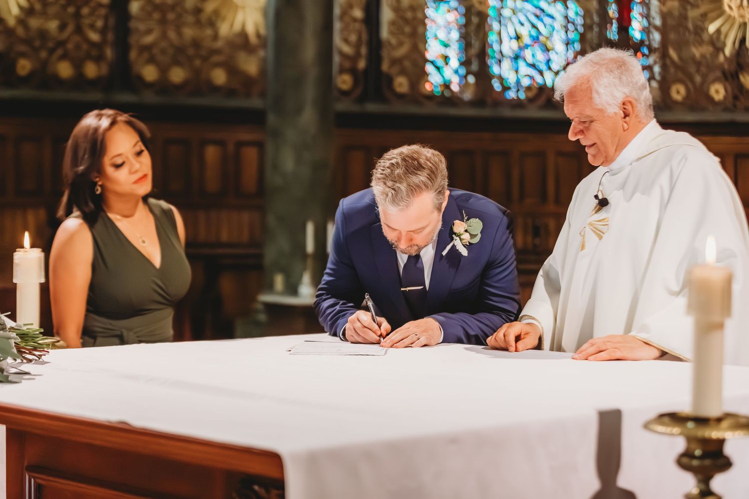 Wedding ceremony participants signing official documents at an altar.