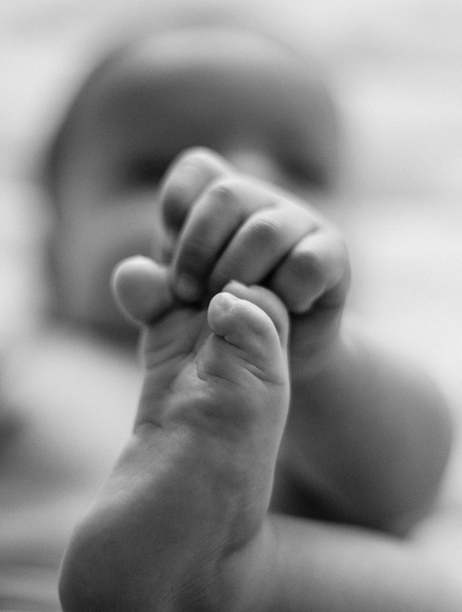 A series of black and white close-up photographs showing small clenched fists in a repeating pattern.