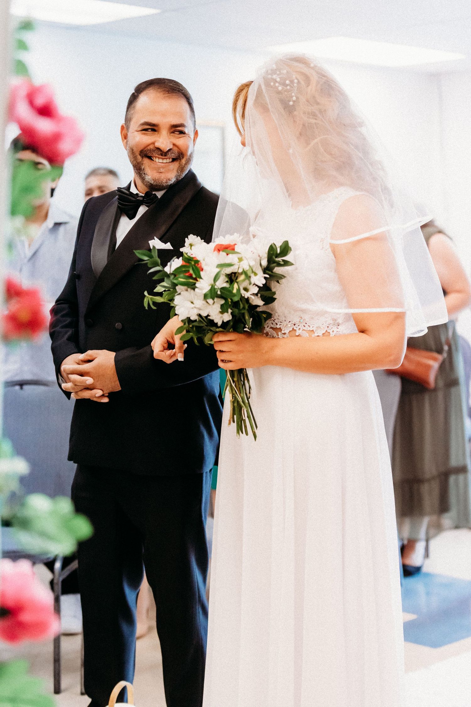 Cérémonie de mariage en intérieur, les mariés échangeant leurs vœux entourés de décorations florales.