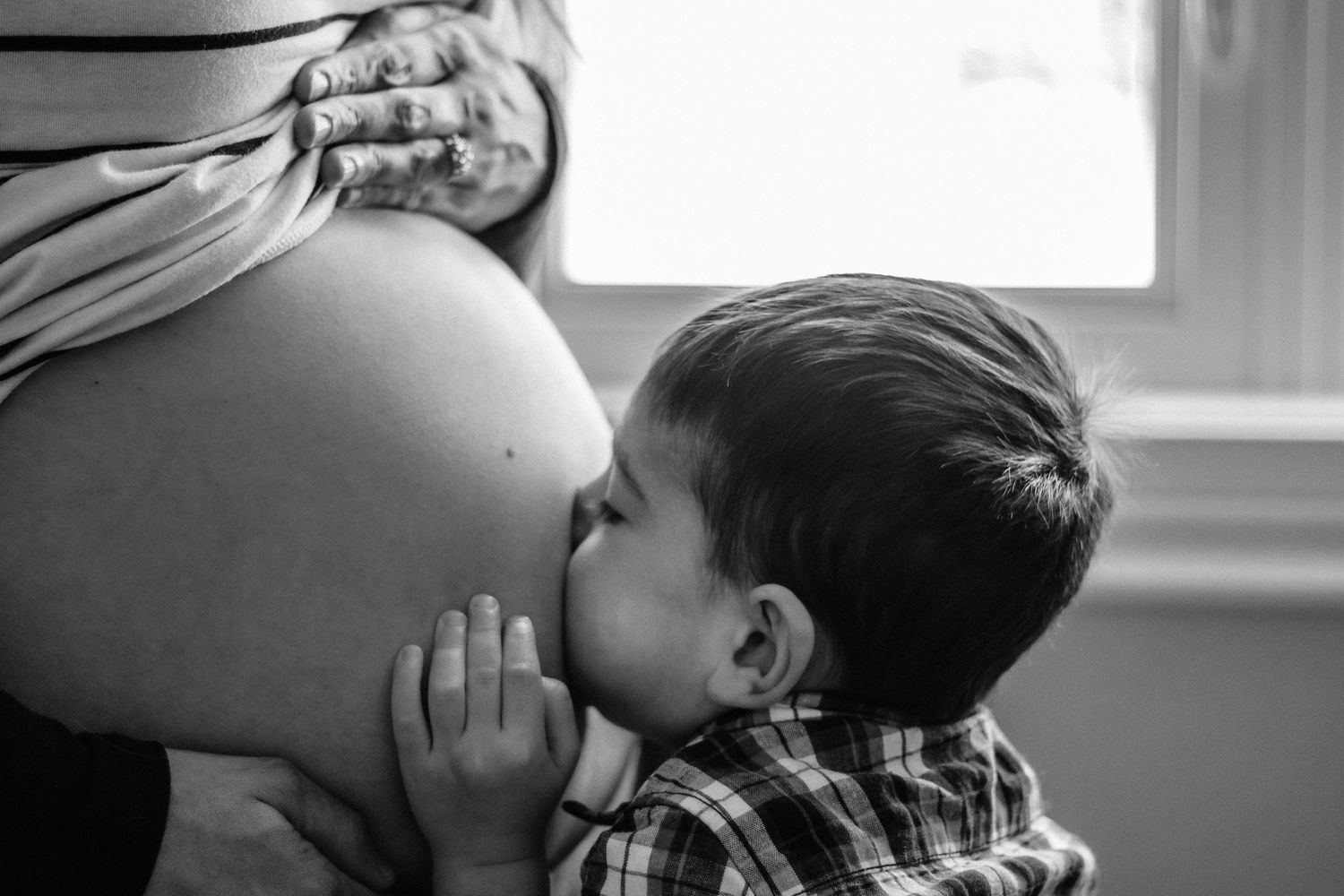 Photos prises sur le vif en noir et blanc, capturant de tendres moments entre une mère enceinte et son premier enfant.