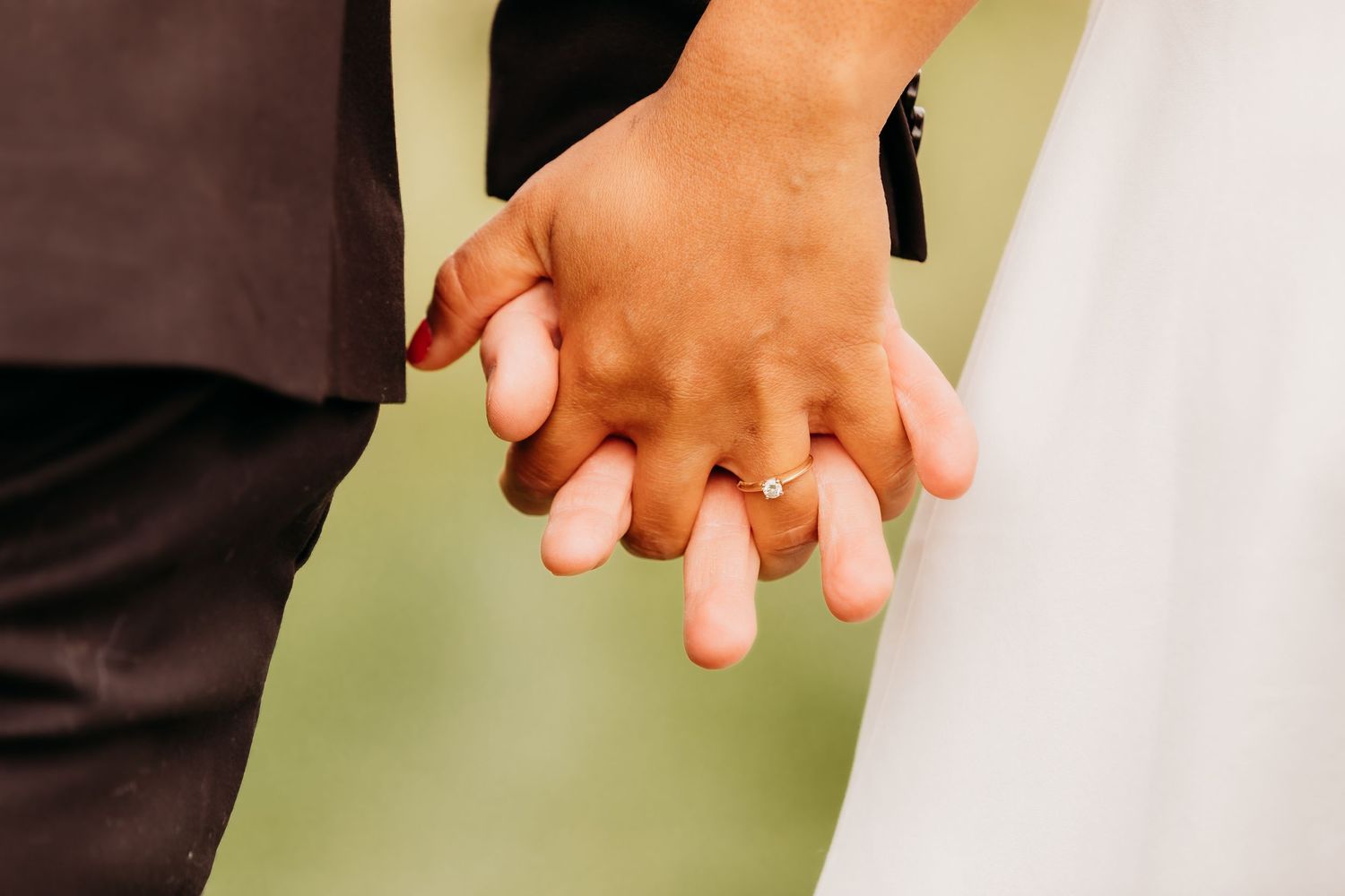 Gros plan sur deux mains se tenant par les doigts entrelacés lors d'une cérémonie de mariage.