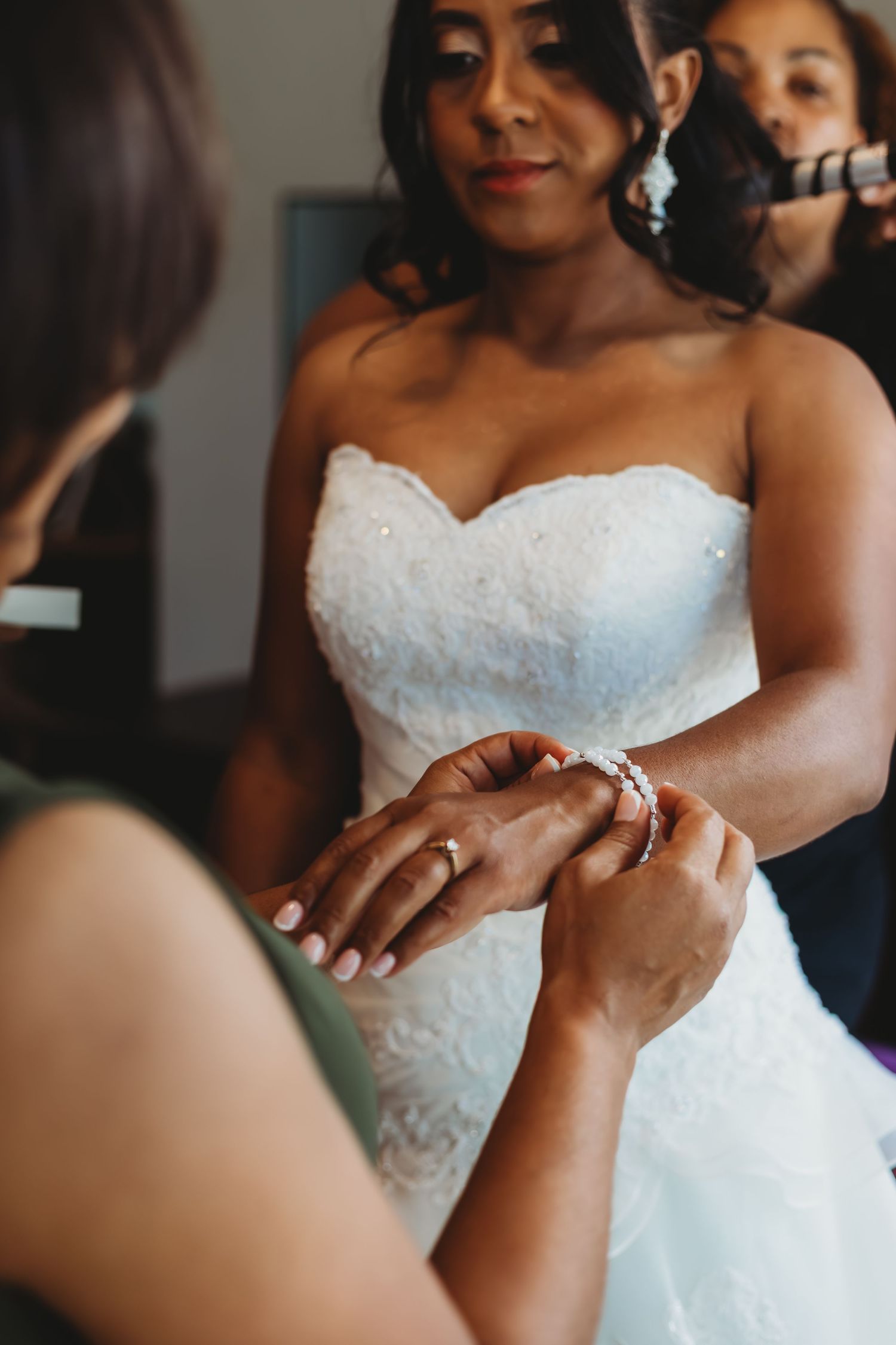Close-up detail of hands adjusting a white lace wedding dress.