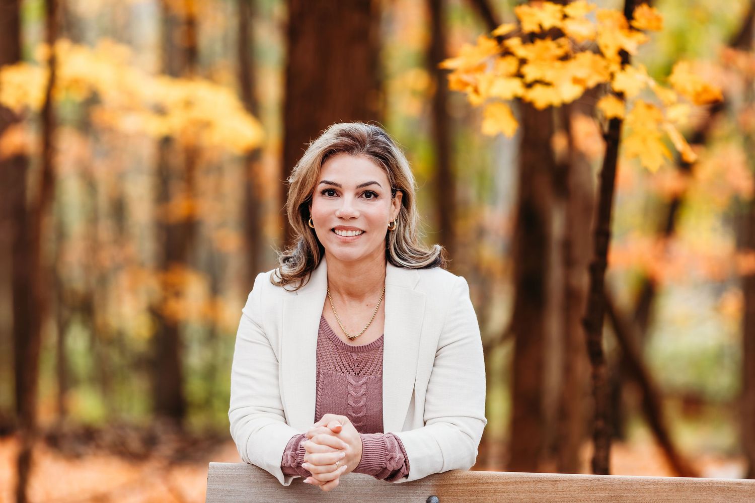 Professional autumn outdoor portrait session featuring warm golden lighting and fall foliage in the background.