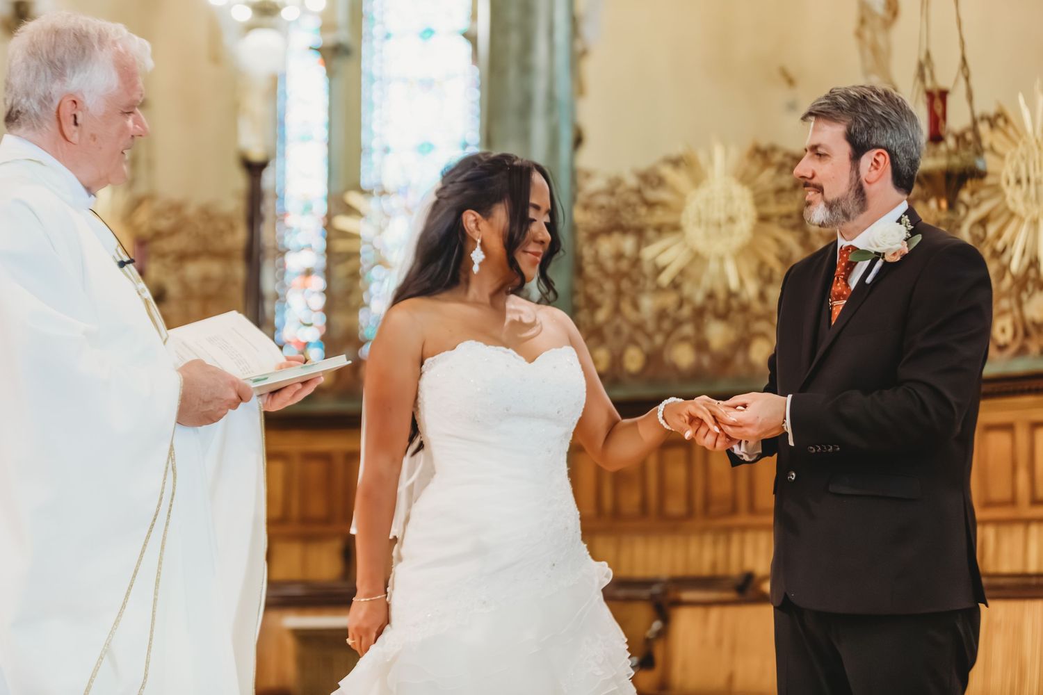 Un couple échange ses vœux lors d'une cérémonie intime dans une église aux vitraux.