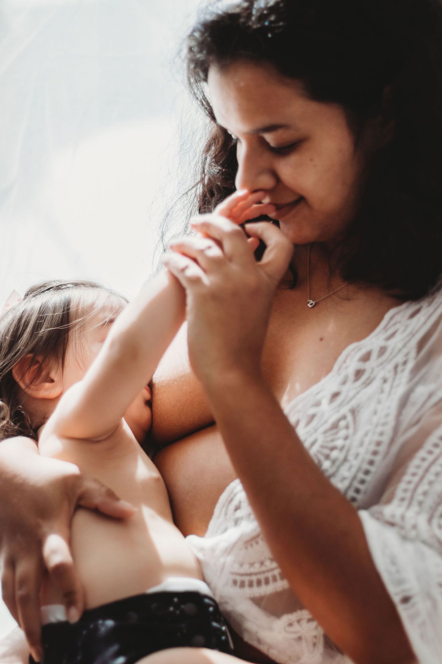 Mother in white lace dress sharing tender moments with her baby in a series of intimate photographs.