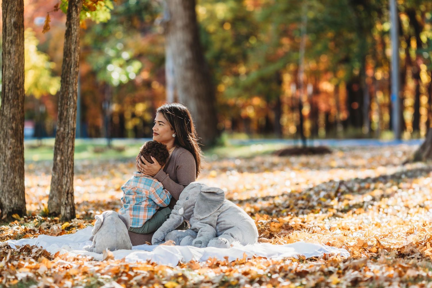 Autumn engagement photo session in a sunlit forest with fallen leaves.