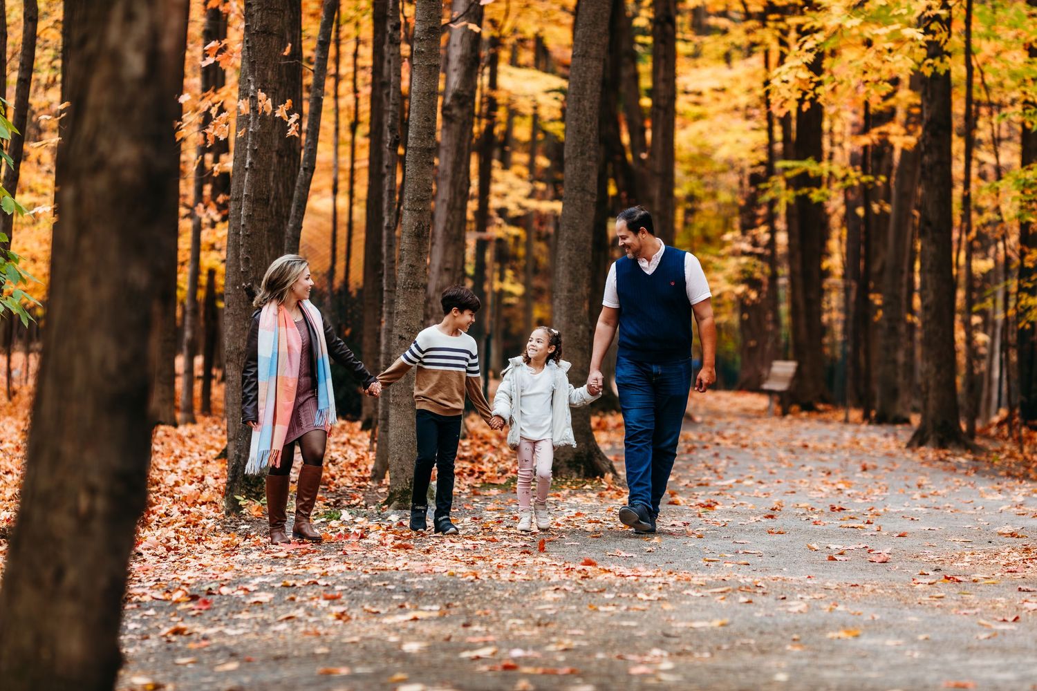 Vue panoramique imprenable sur une famille jouant dans une forêt aux teintes dorées d'automne.