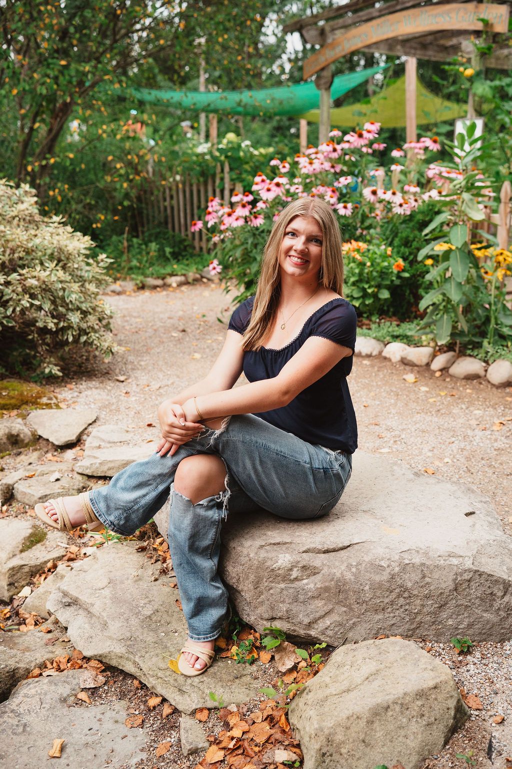 A stone ledge surrounded by lush greenery and pink flowers in a tranquil garden setting.