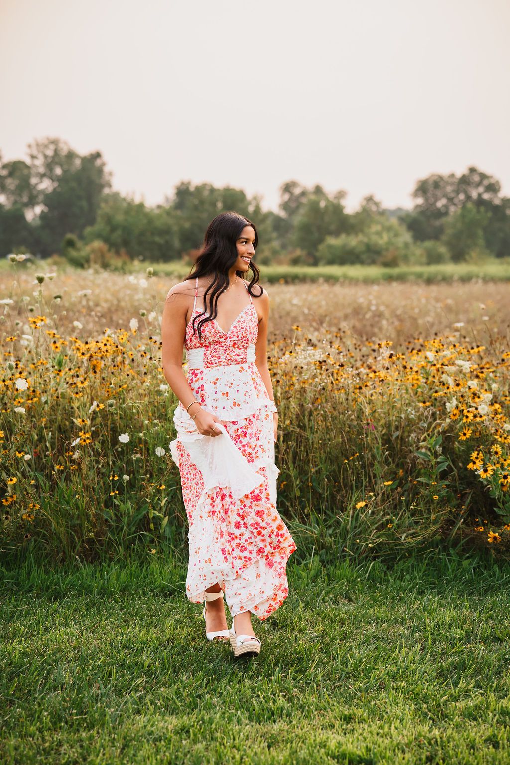 A flowing white and red floral dress creates movement in a golden meadow filled with summer wildflowers.
