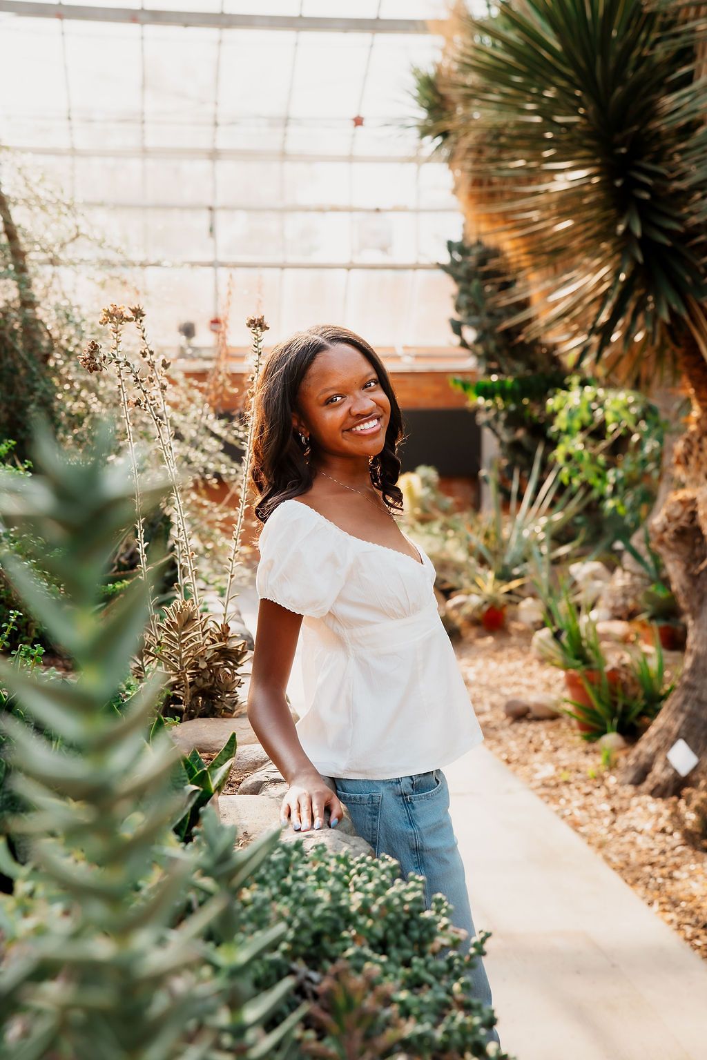 A joyful moment captured in a garden setting with tropical plants and a sunlit concrete path.