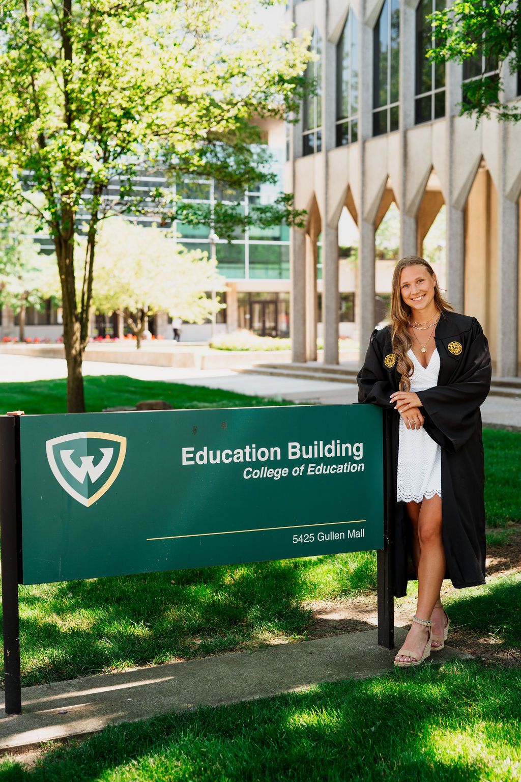 College of Education building sign with landscaping and green grass in front of academic building entrance.