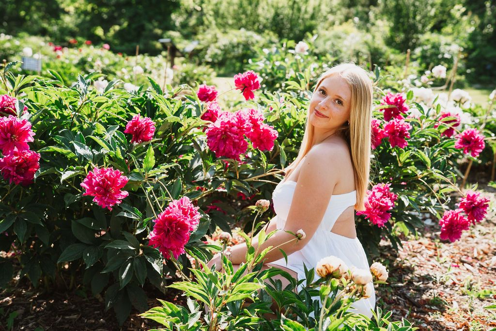 Portrait session in a rose garden with bright magenta blooms.