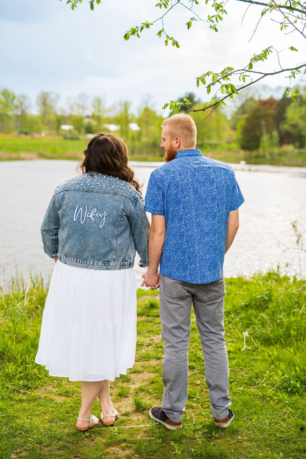 A couple stands together by a lake wearing matching denim and white outfits in a series of romantic photos.
