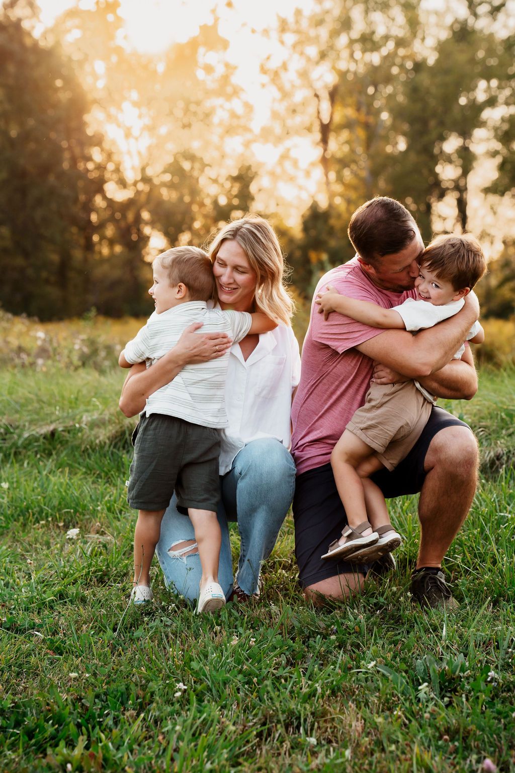 Family relaxes together on grassy hill during sunset photoshoot.