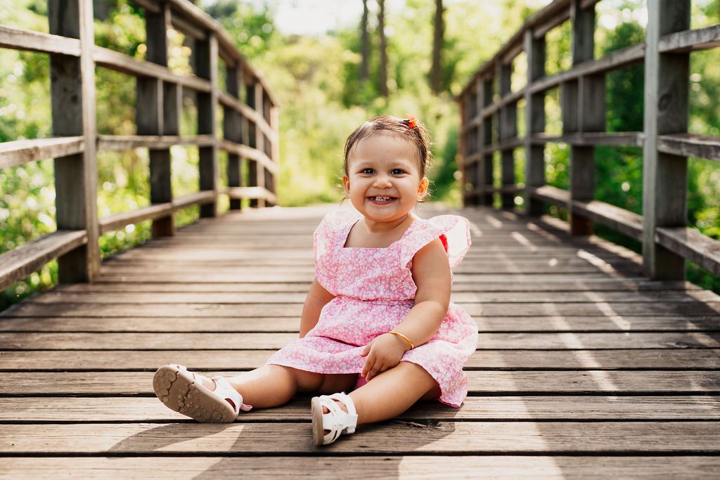 A series of photos showing a child in a pink dress sitting on a wooden boardwalk surrounded by lush greenery.