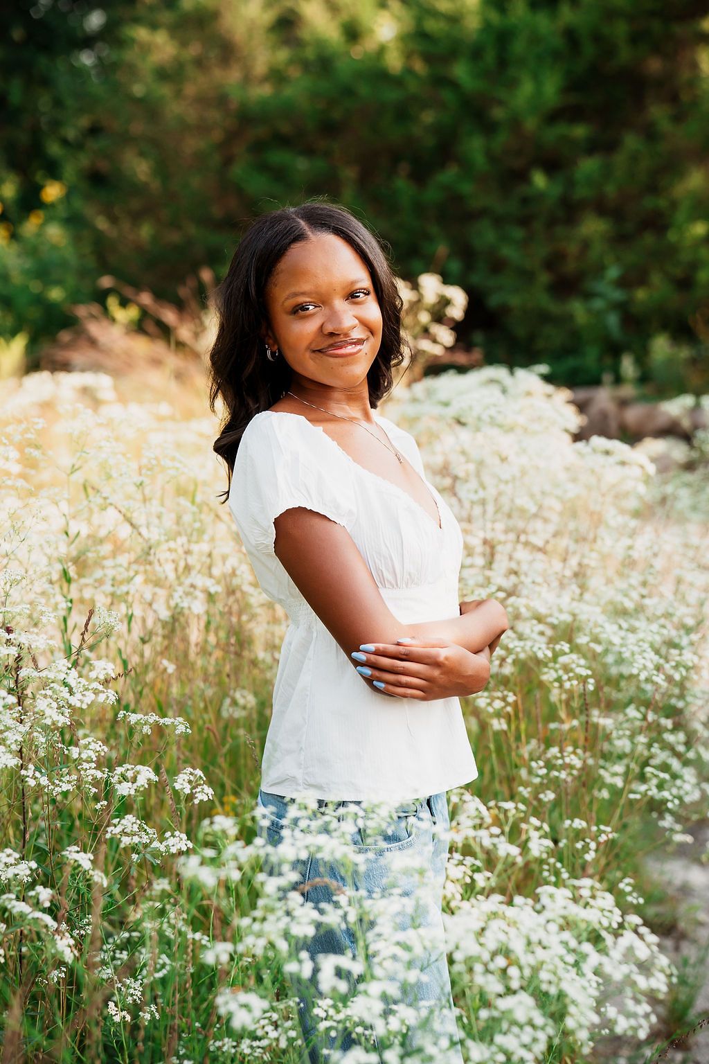 Summer portrait in a field of white wildflowers with natural lighting and green background.