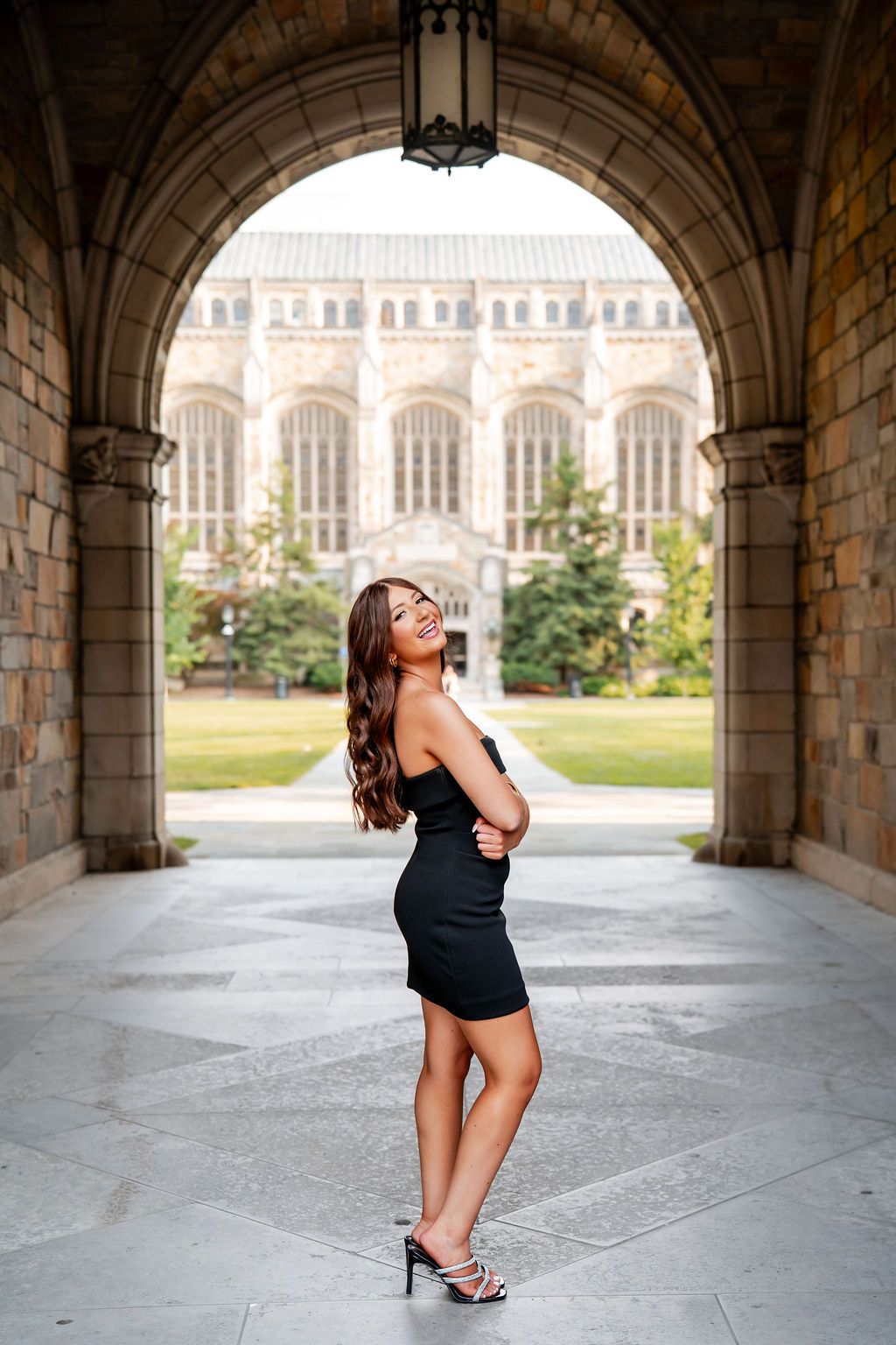 A dancer performs graceful poses under a stone archway at a historic university building.