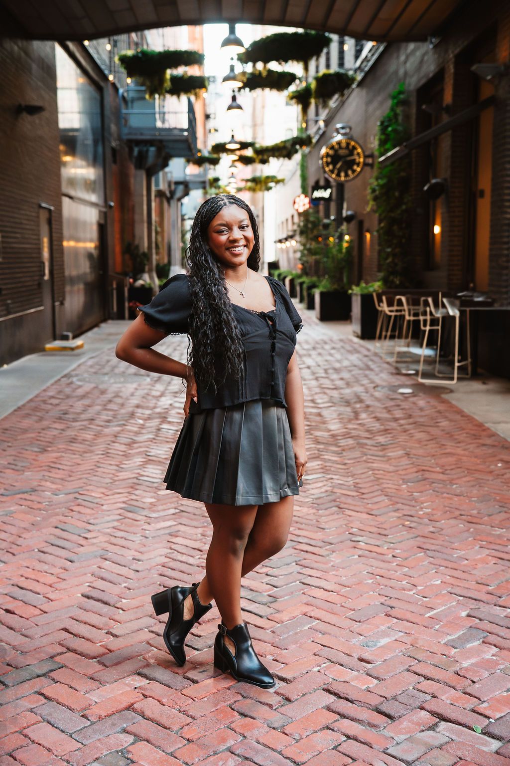 Lifestyle photography on a brick-paved street featuring a black dress and stylish boots.