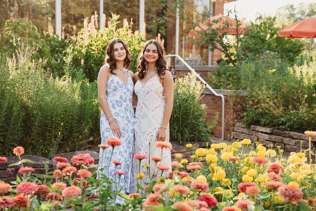 Two people stand in a vibrant garden filled with colorful tulips and spring flowers during golden hour.