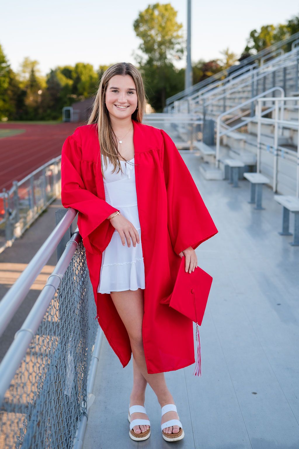 A series of photos showing someone in a bright red blazer and white top posing on bleachers at a sports field.