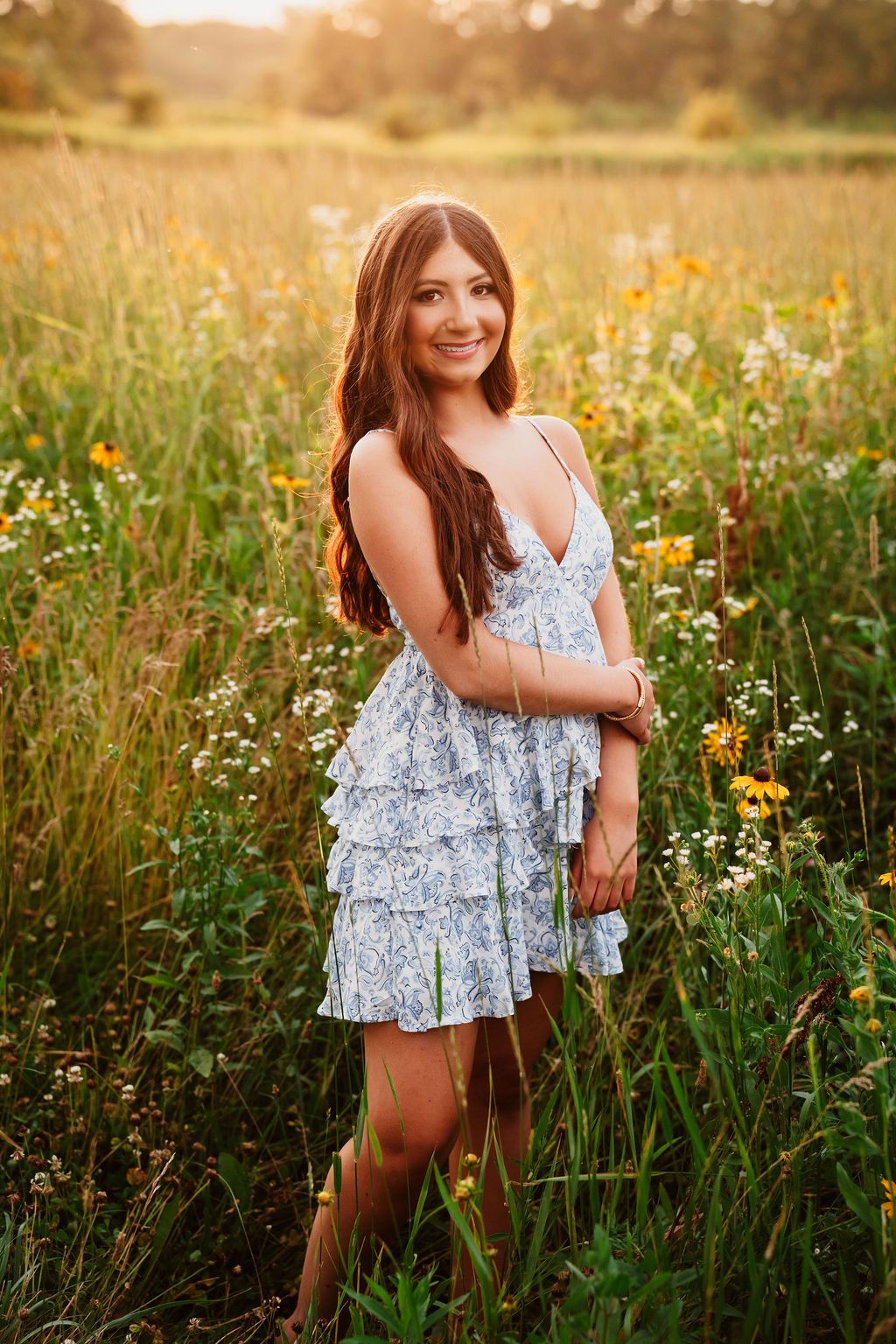 Whimsical summer portrait among wildflowers and tall grass at sunset.