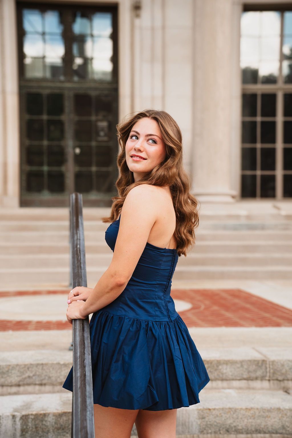 Multiple shots of someone in a navy peplum top posing against a classical building exterior with columns.