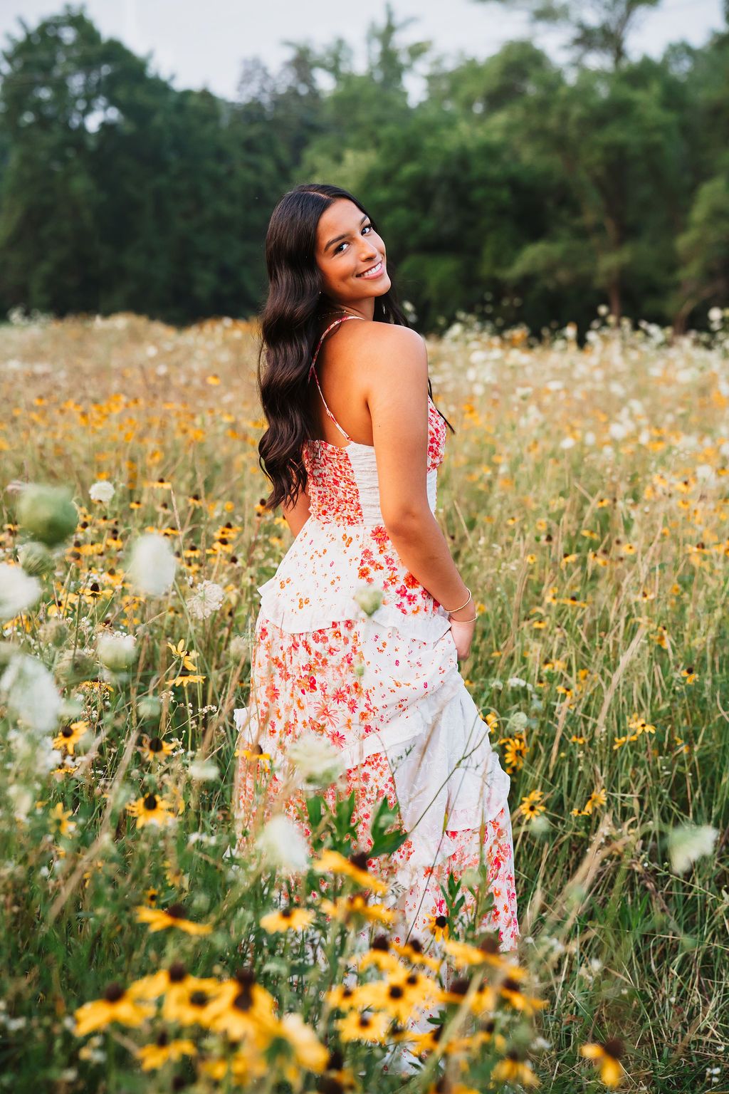 A floral sundress stands out against a vibrant wildflower meadow filled with yellow blooms and white poppies.
