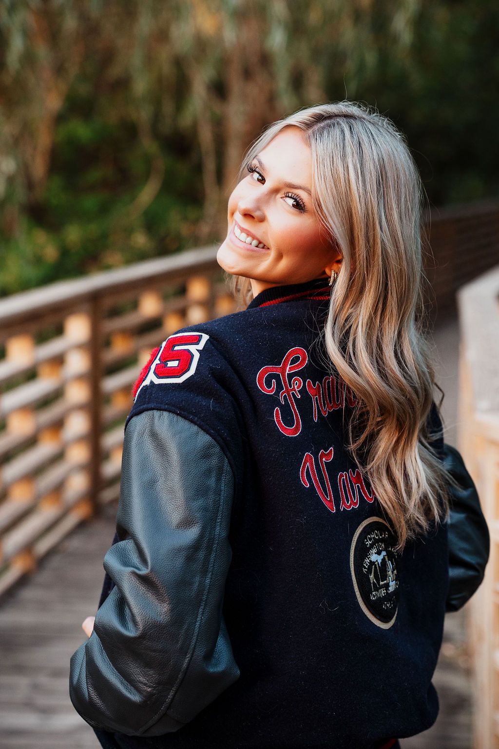 Stylish letterman jacket photoshoot on a wooden bridge during golden hour. direct sunlight senior photos golden hour livonia Franklin