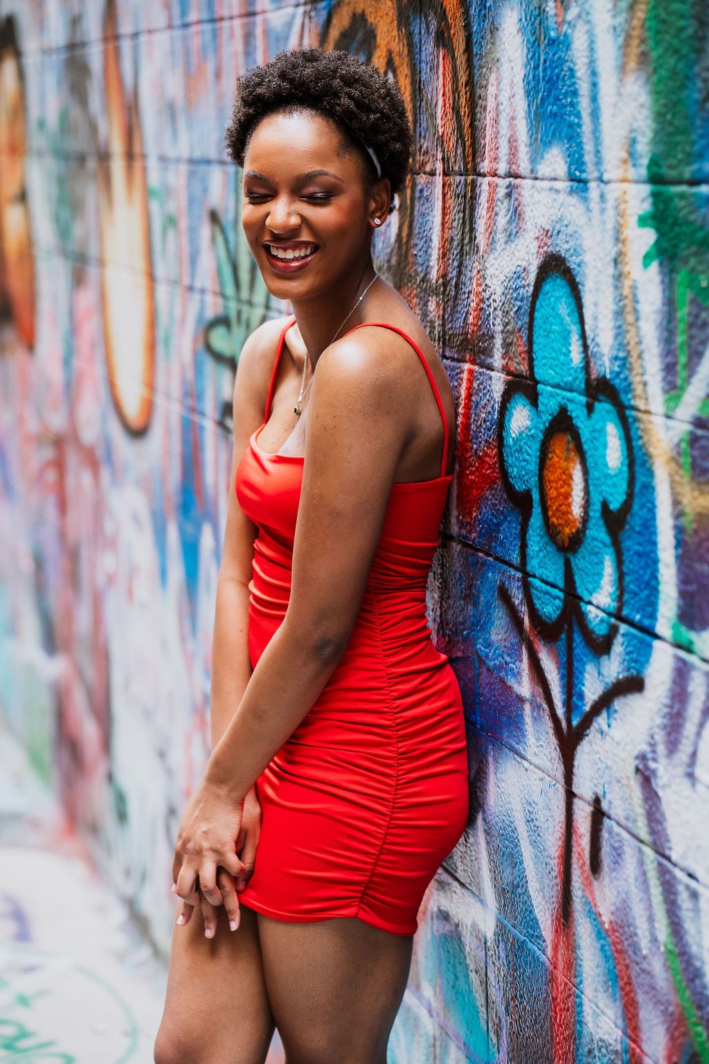 Woman in red swimsuit poses against colorful graffiti wall in three similar shots.