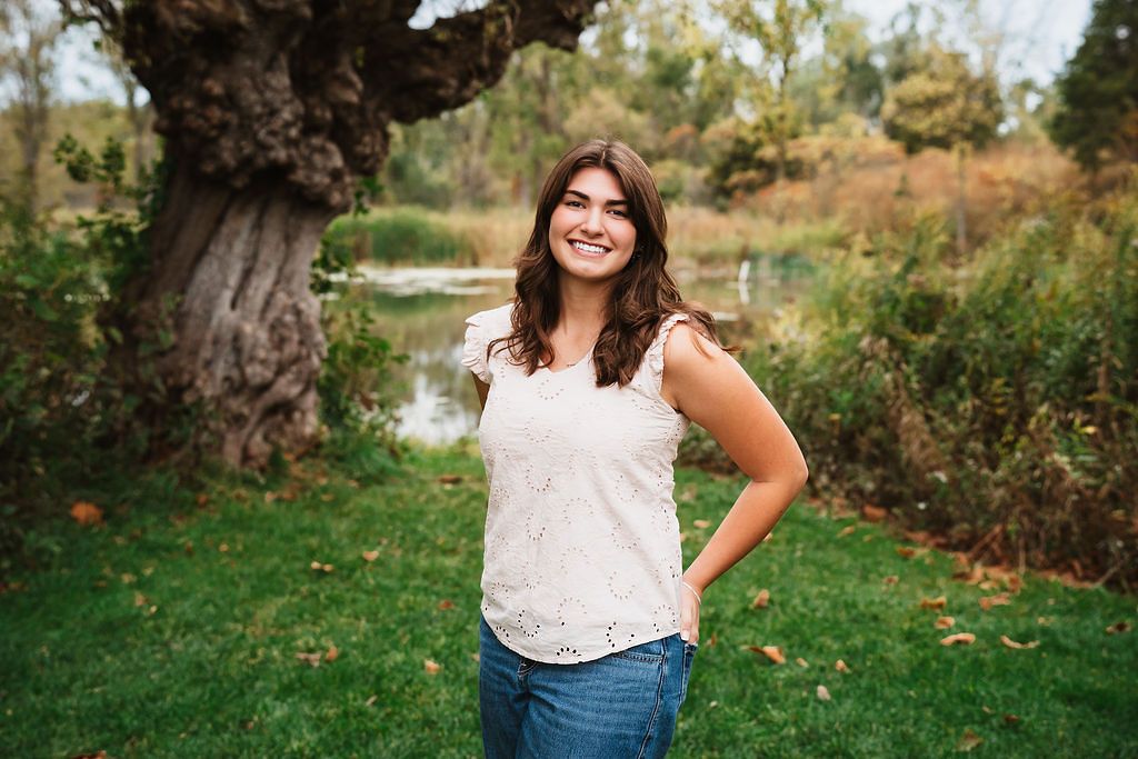 White lace top and denim casual portrait against natural greenery background.