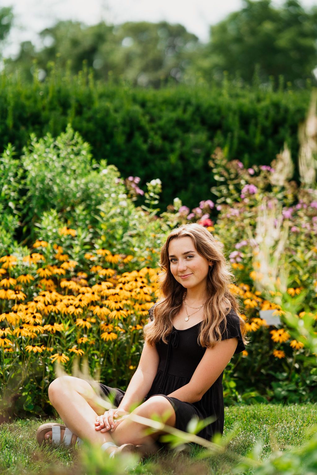 A scenic outdoor photo shoot in a garden filled with vibrant yellow flowers and lush greenery.